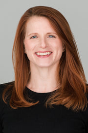 Smiling woman, brown hair, wearing clothing, representing WeNatal's focus on wellness and prenatal care products.